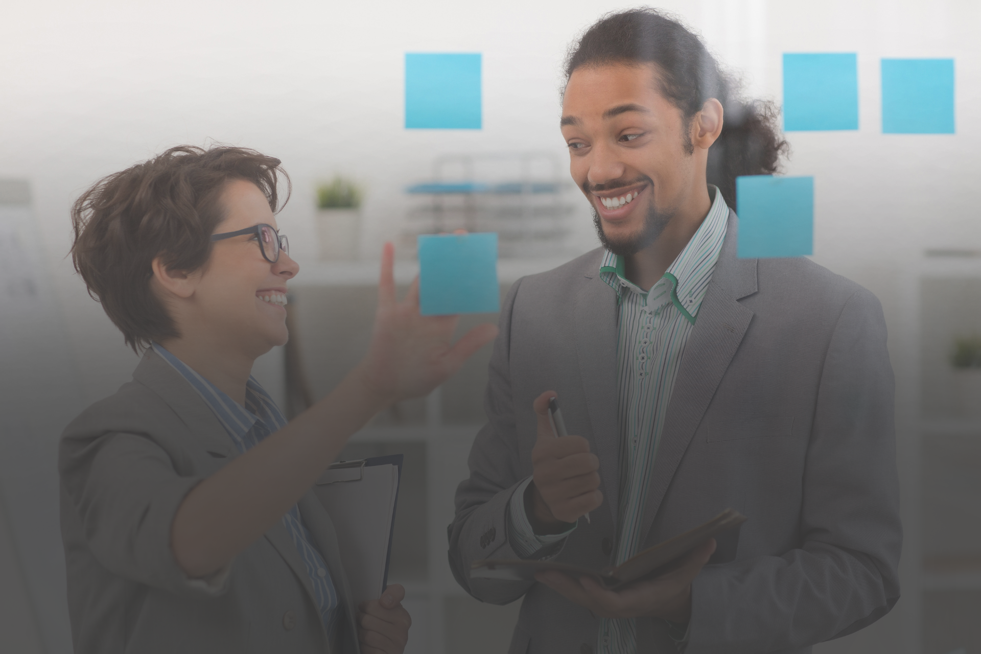 homem e mulher conversando em frente a um quadro de post its