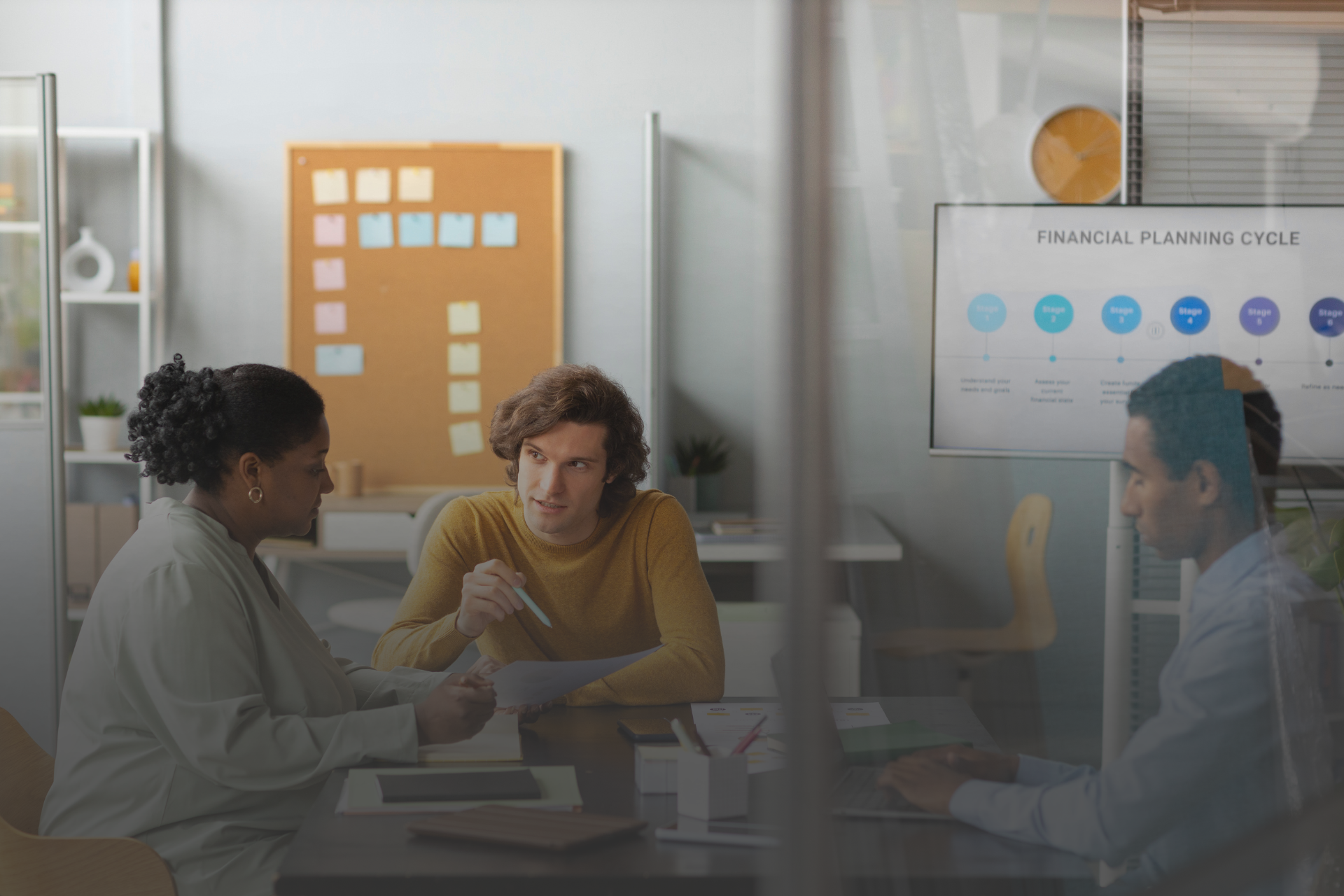 tres pessoas conversando sentadas em uma mesa em um ambiente corporativo 