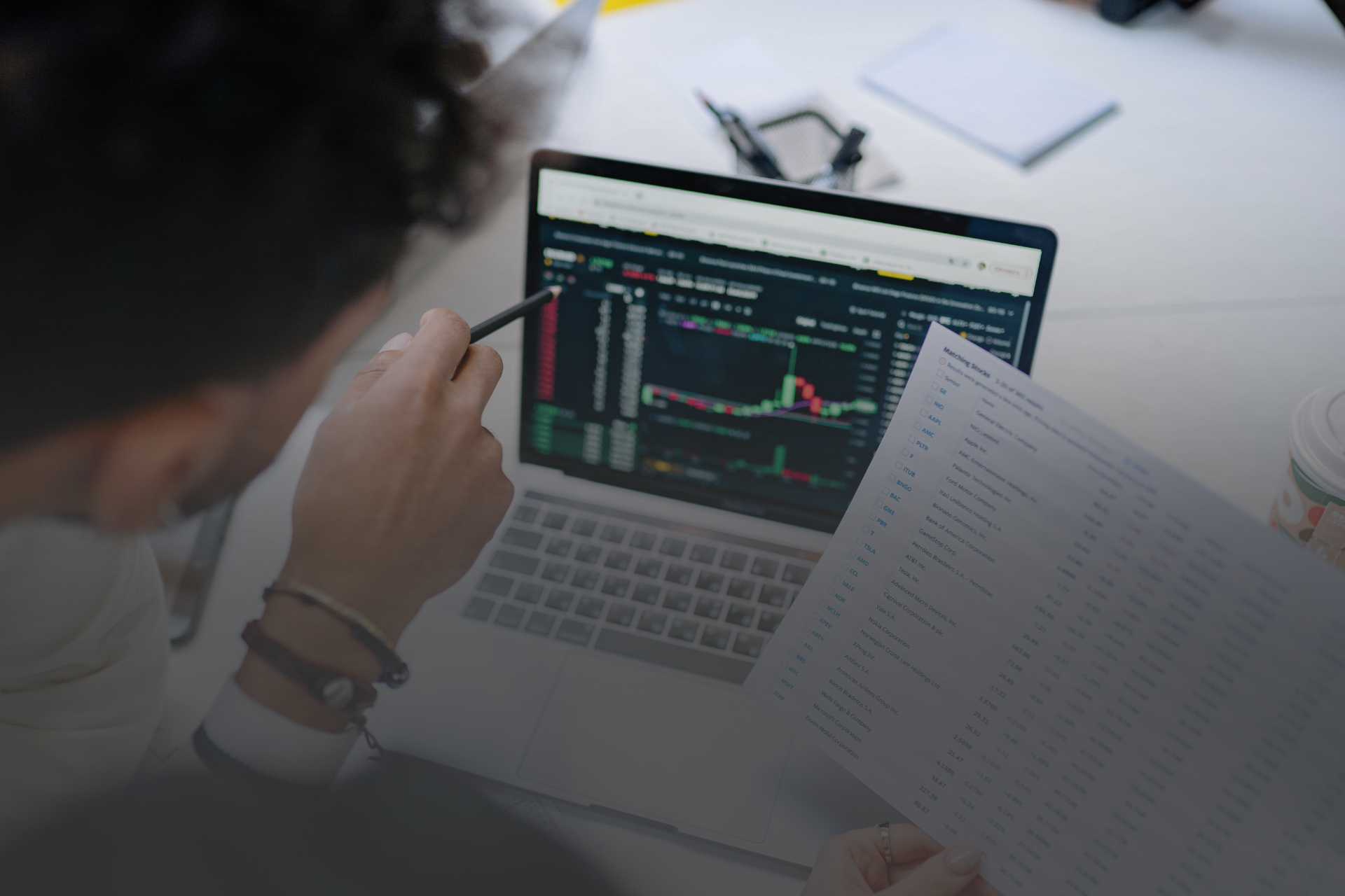 notebook aberto com gráficos na tela e uma mão apontando