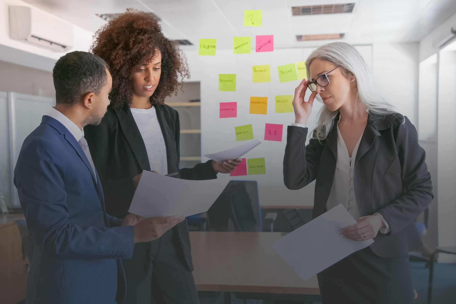 tres pessoas conversando em um ambiente corporativo com papéis nas mãos