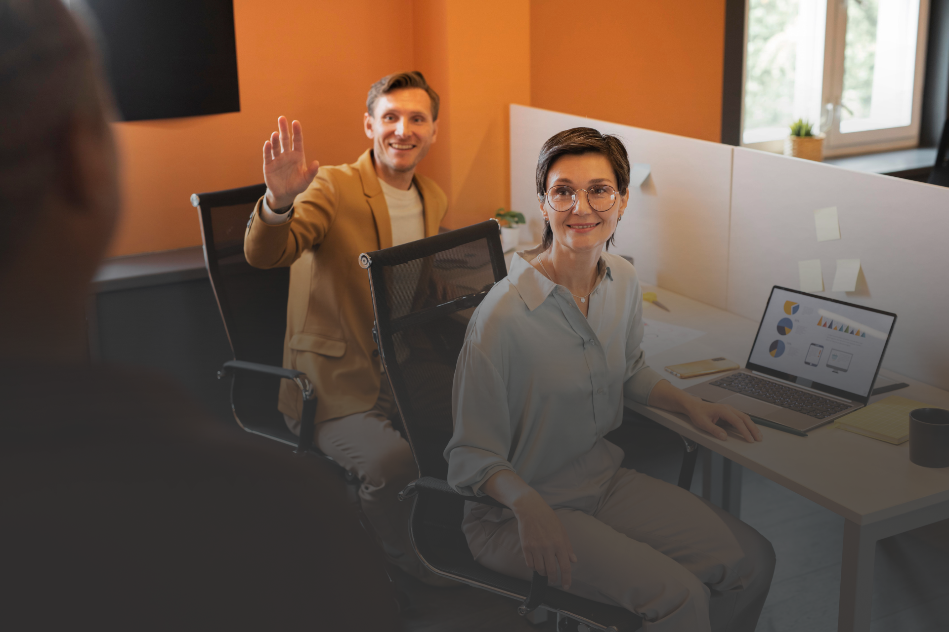 duas pessoas olhando para alguém fora da imagem em um ambiente corporativo