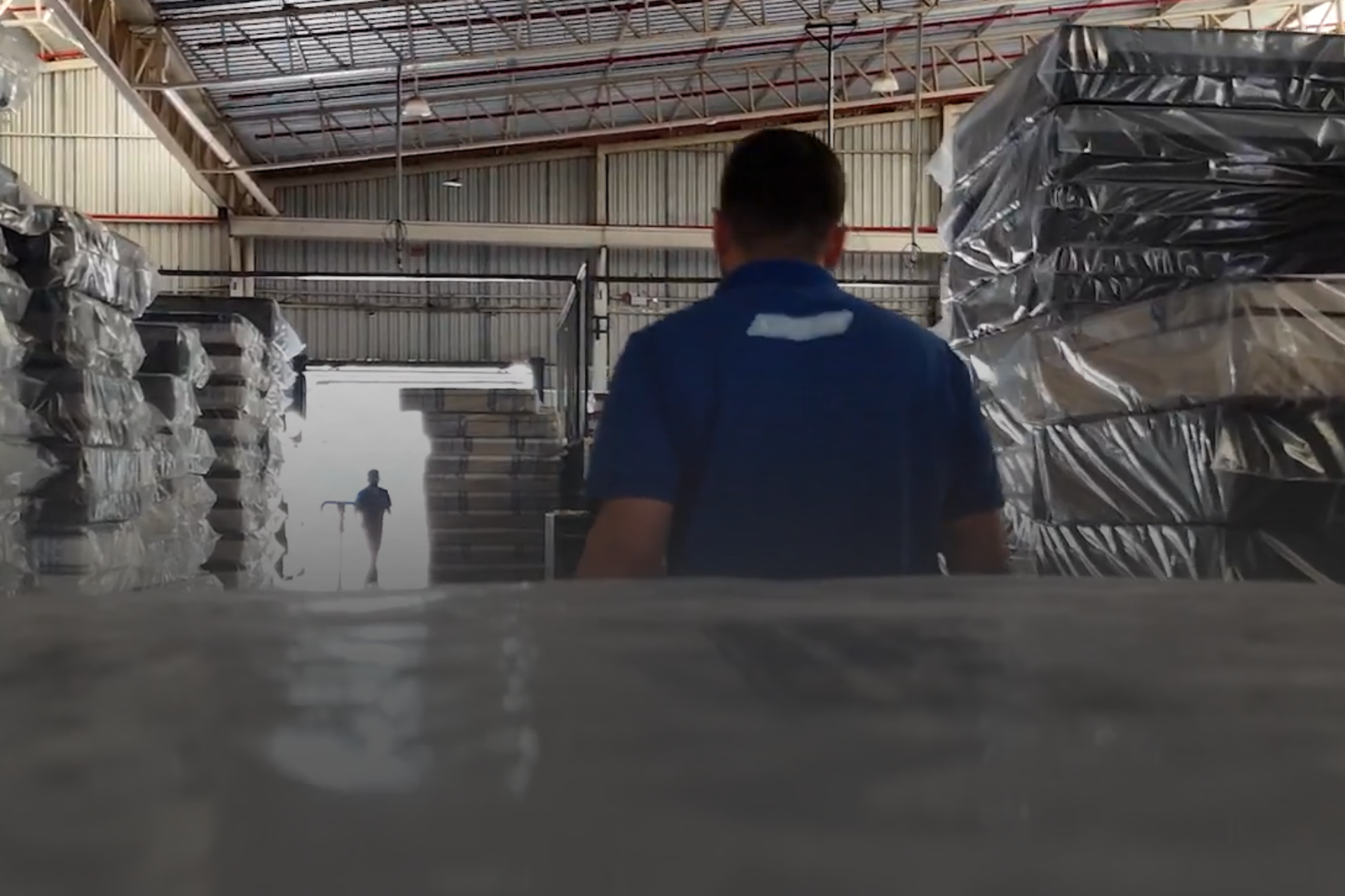 homem puxando um carrinho com colchões em uma fábrica
