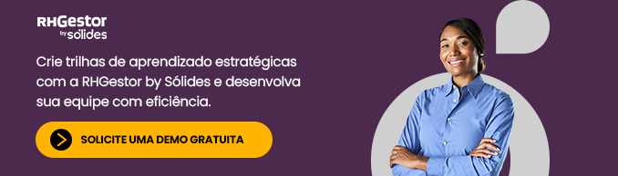 mulher de camisa de botões azul de braços cruzados em frente a um fundo roxo